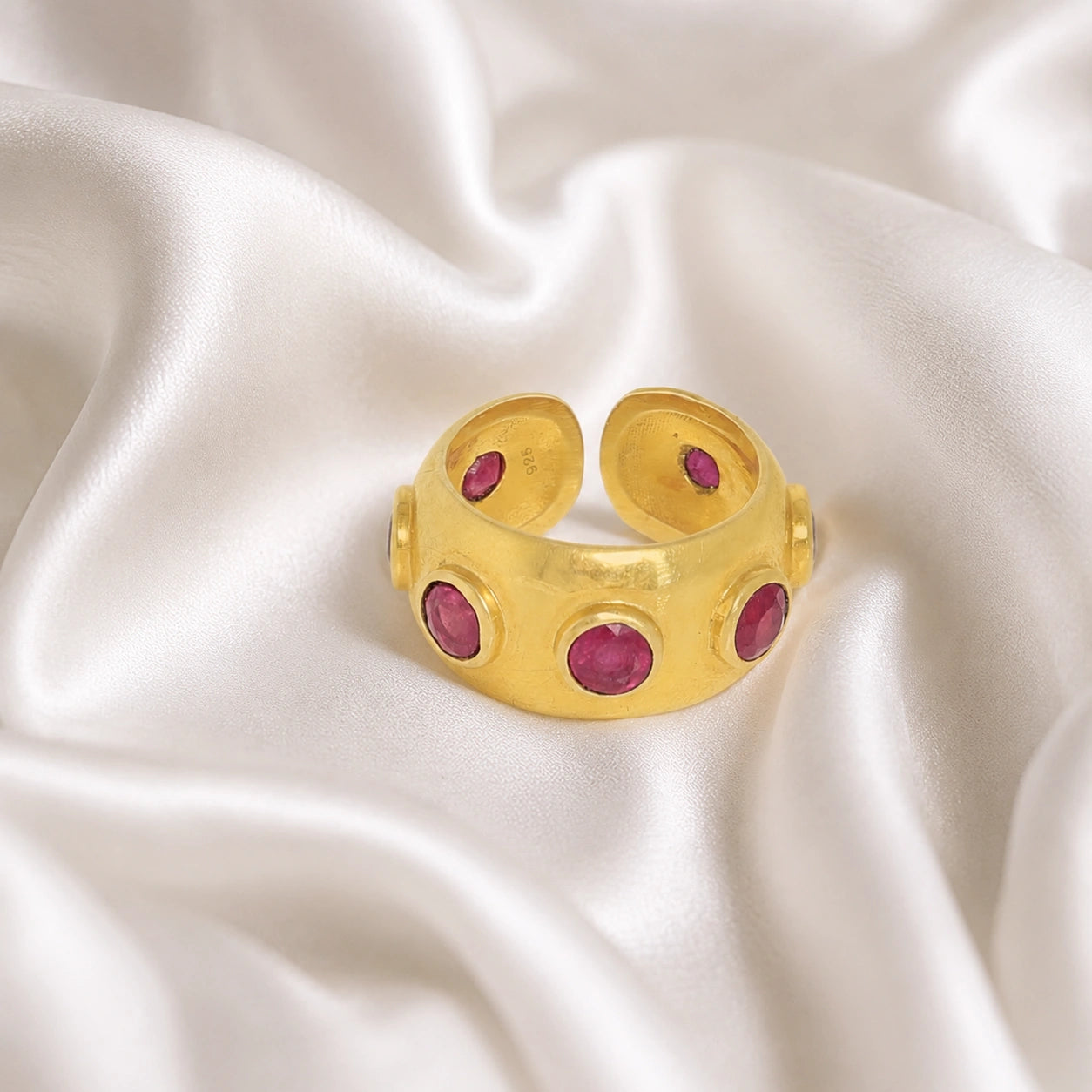 Silver_ruby_ring_in_gold_plated_silver_with_bezel_set_ruby_stones_at_front_view_on_soft_fabric_background