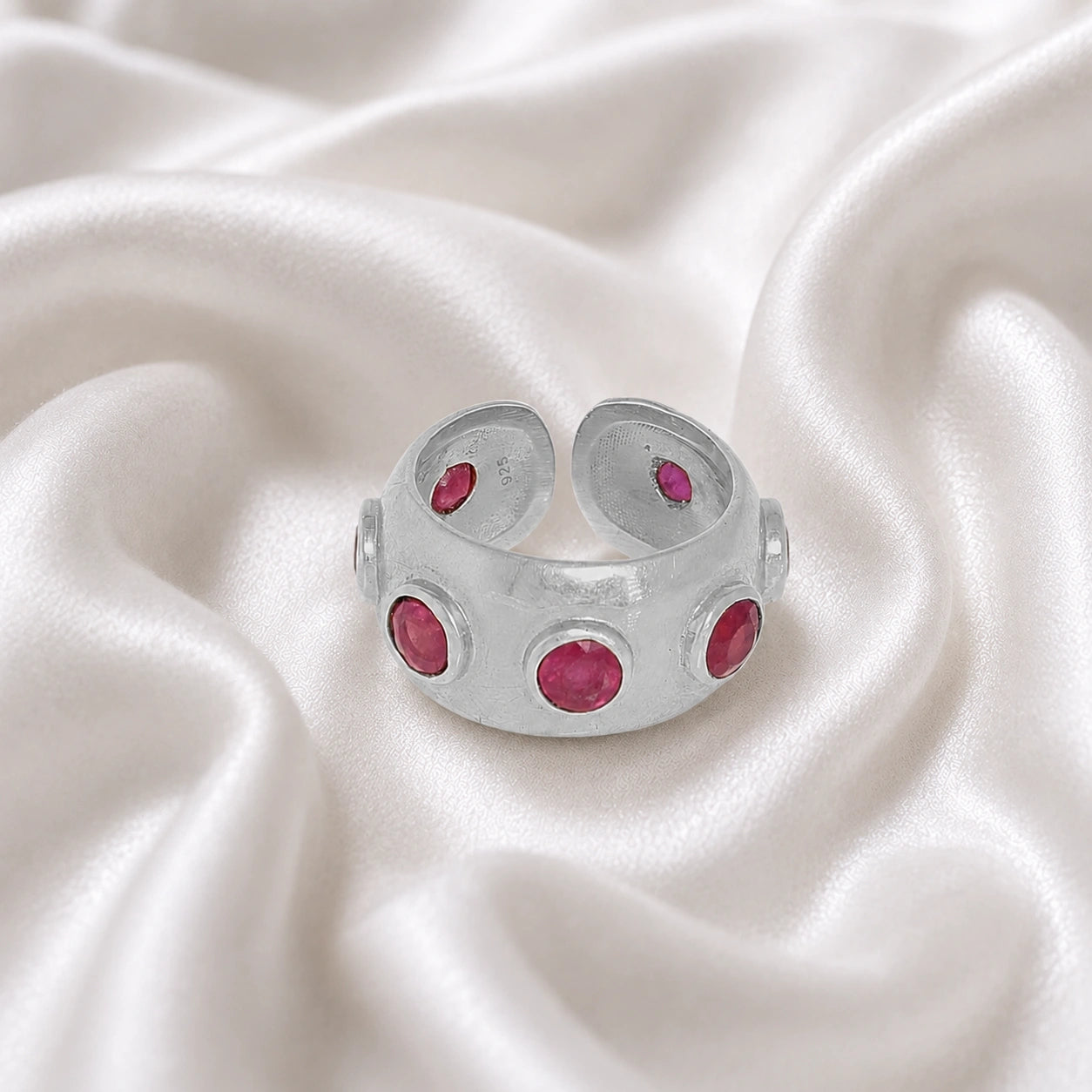 Silver_ruby_ring_in_sterling_silver_with_bezel_set_ruby_stones_at_front_view_on_soft_fabric_background