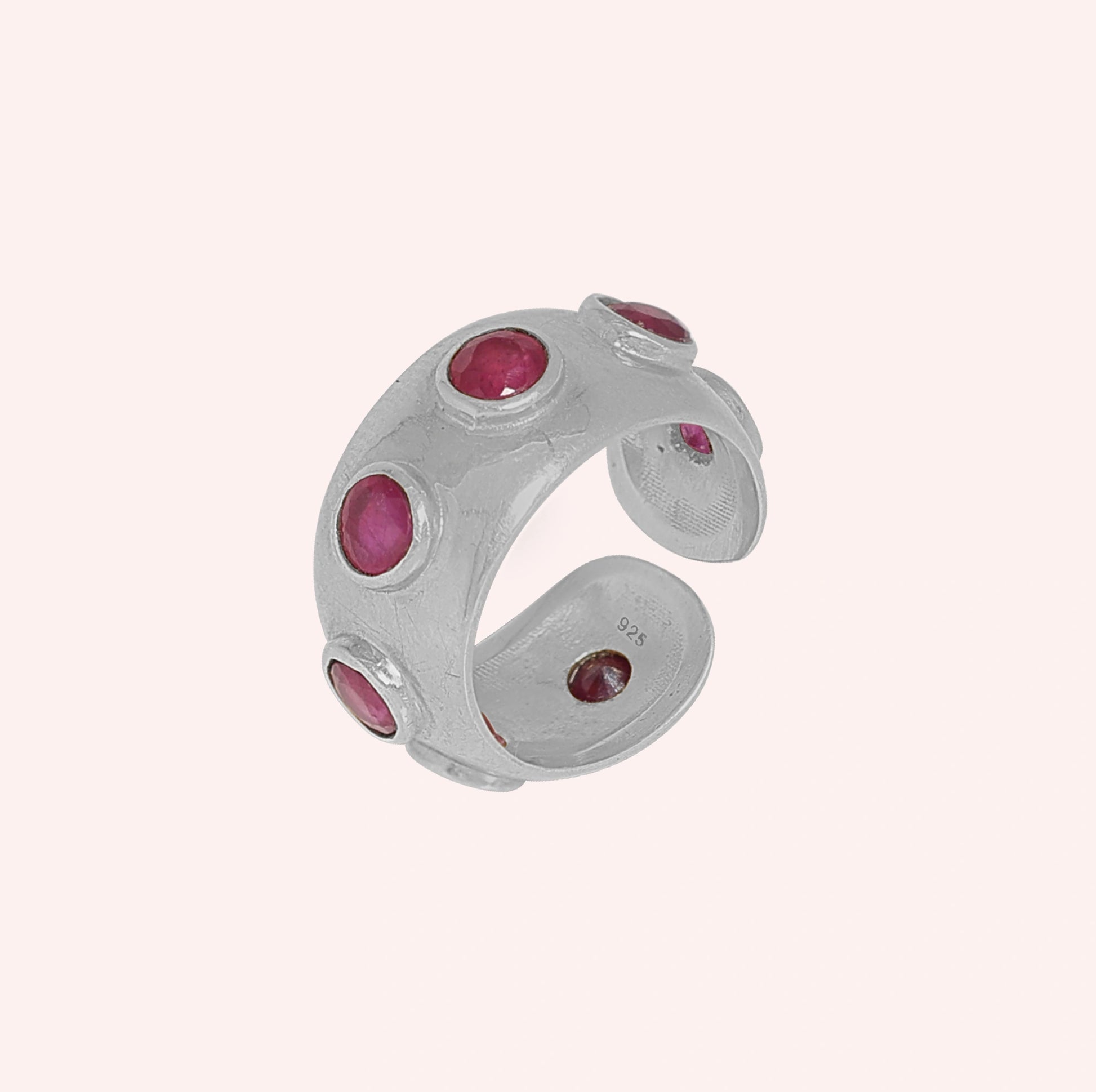 Silver_ruby_ring_in_sterling_silver_with_bezel_set_ruby_stones_at_slight_view_on_solid_pink_background