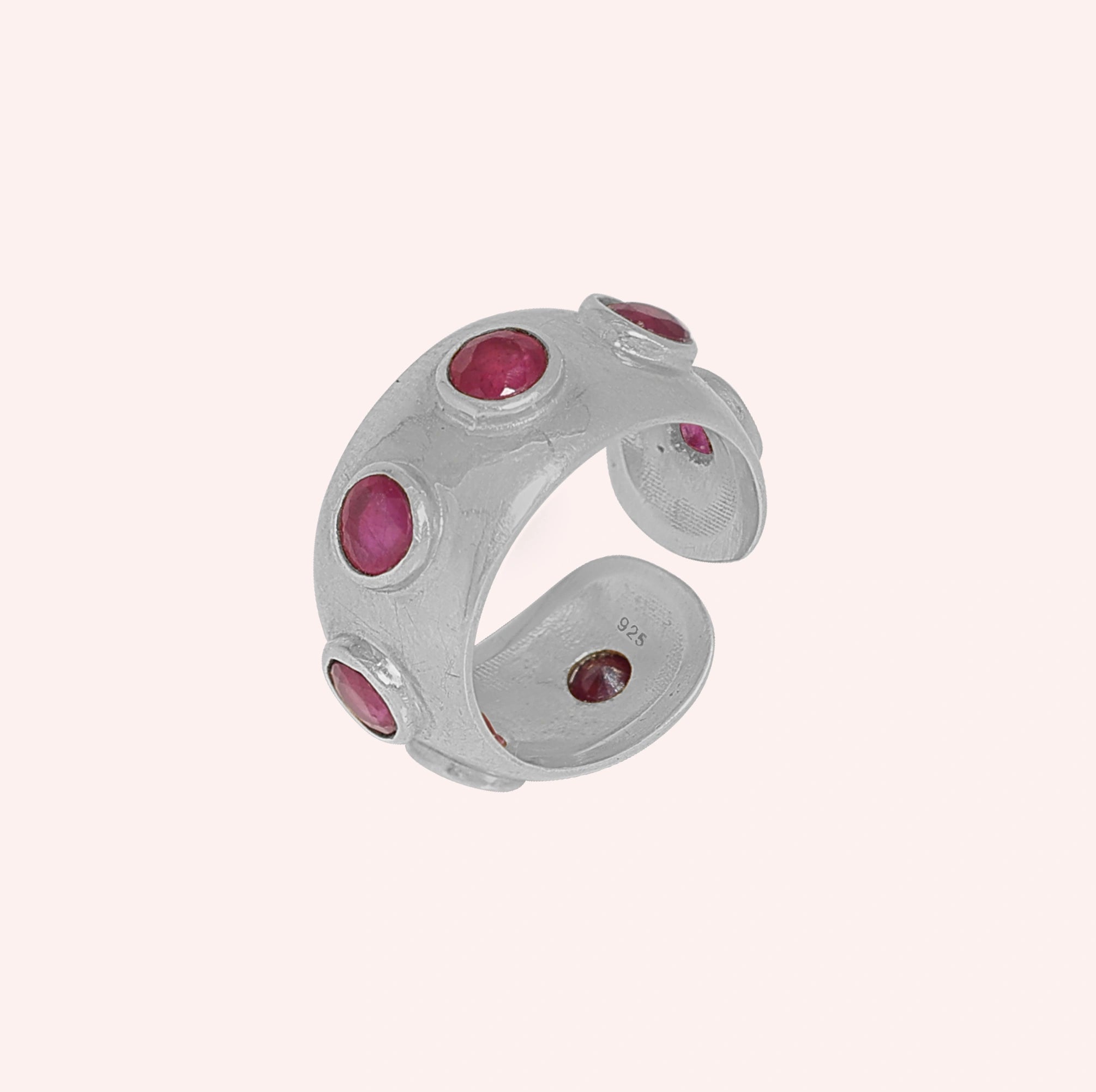 Silver_ruby_ring_in_sterling_silver_with_bezel_set_ruby_stones_at_slight_view_on_solid_pink_background