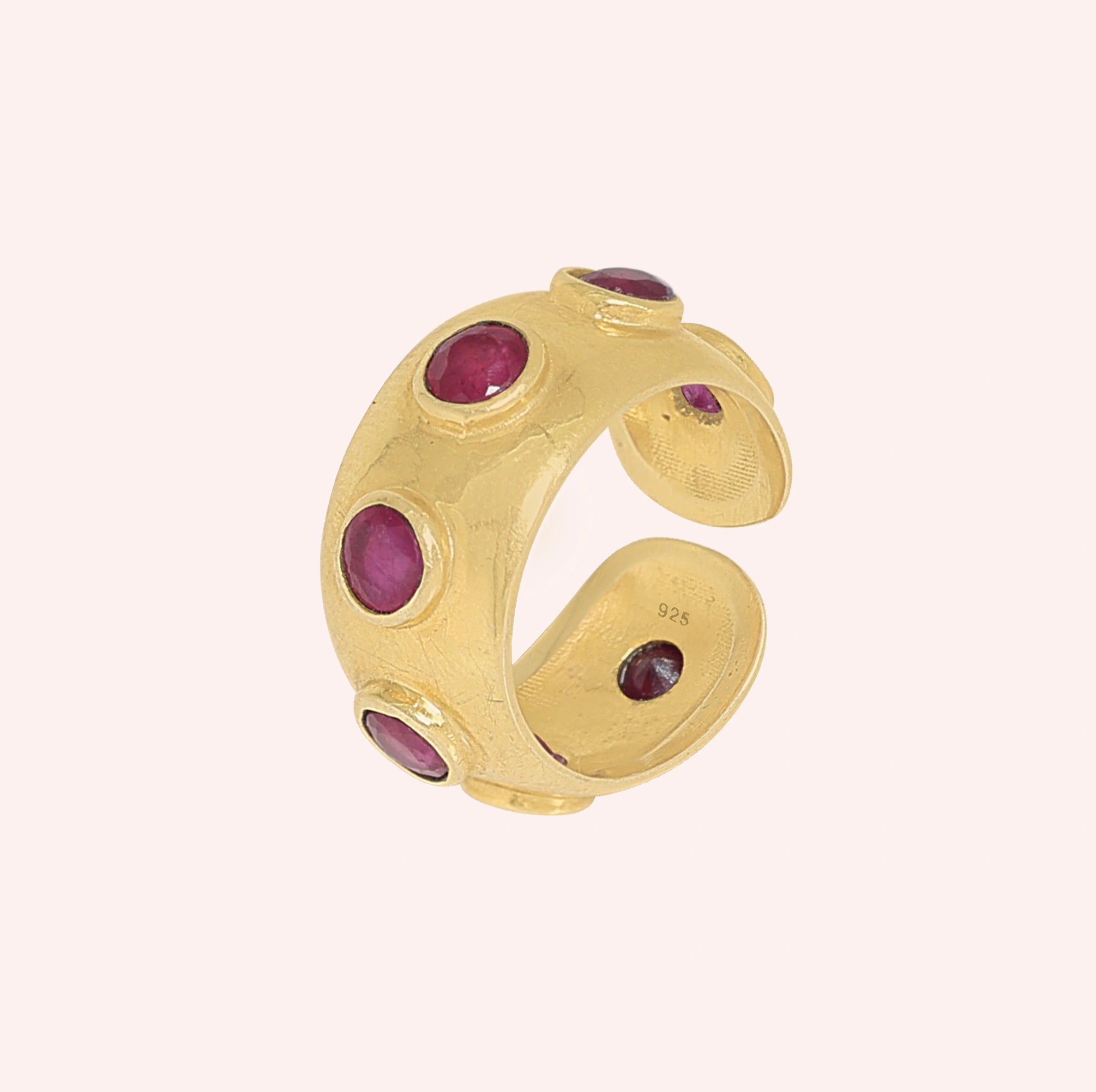 Silver_ruby_ring_in_gold_plated_silver_with_bezel_set_ruby_stones_at_slight_view_on_solid_pink_background