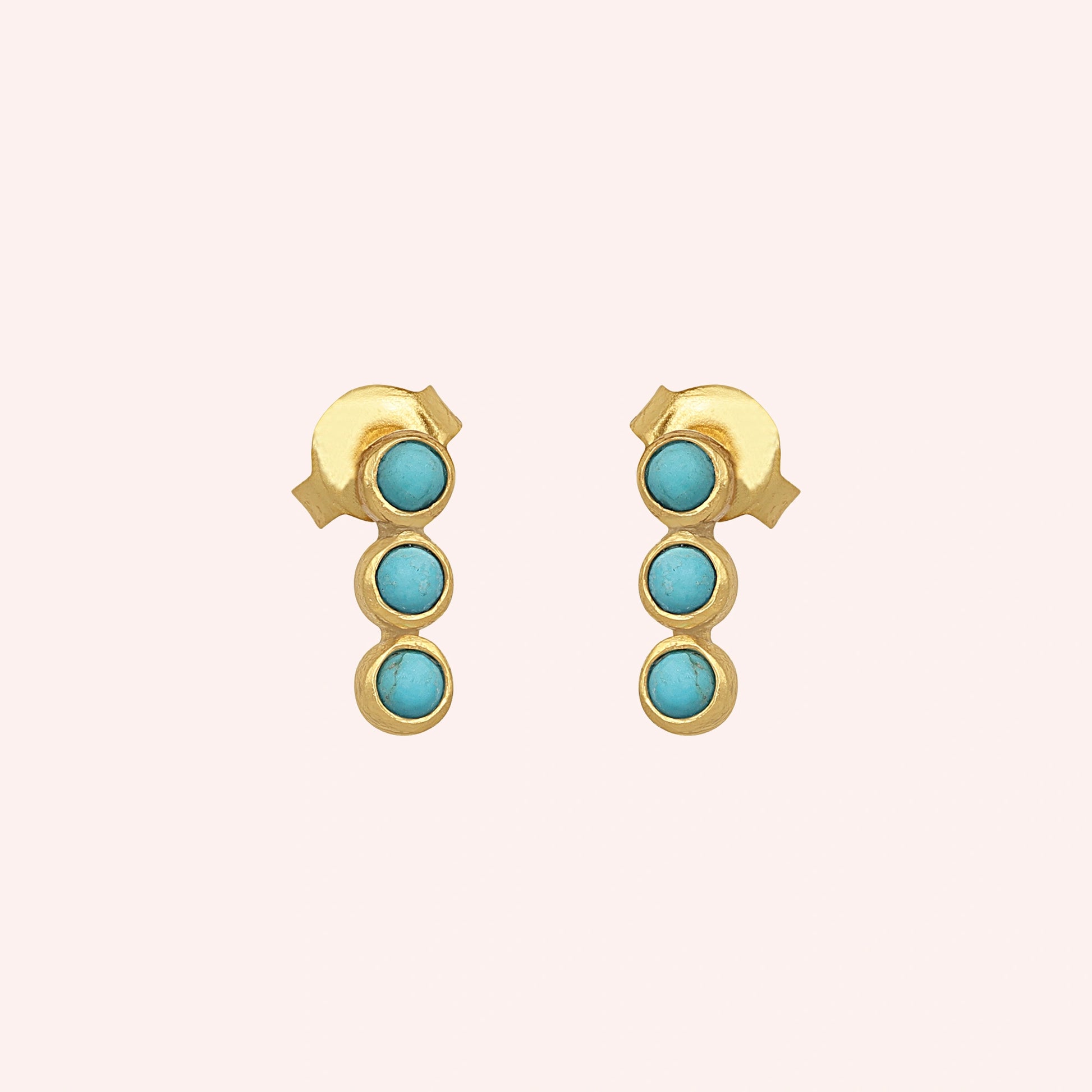 Turquoise earrings featuring three stones on gold-plated silver stud earrings over a pink background front angle