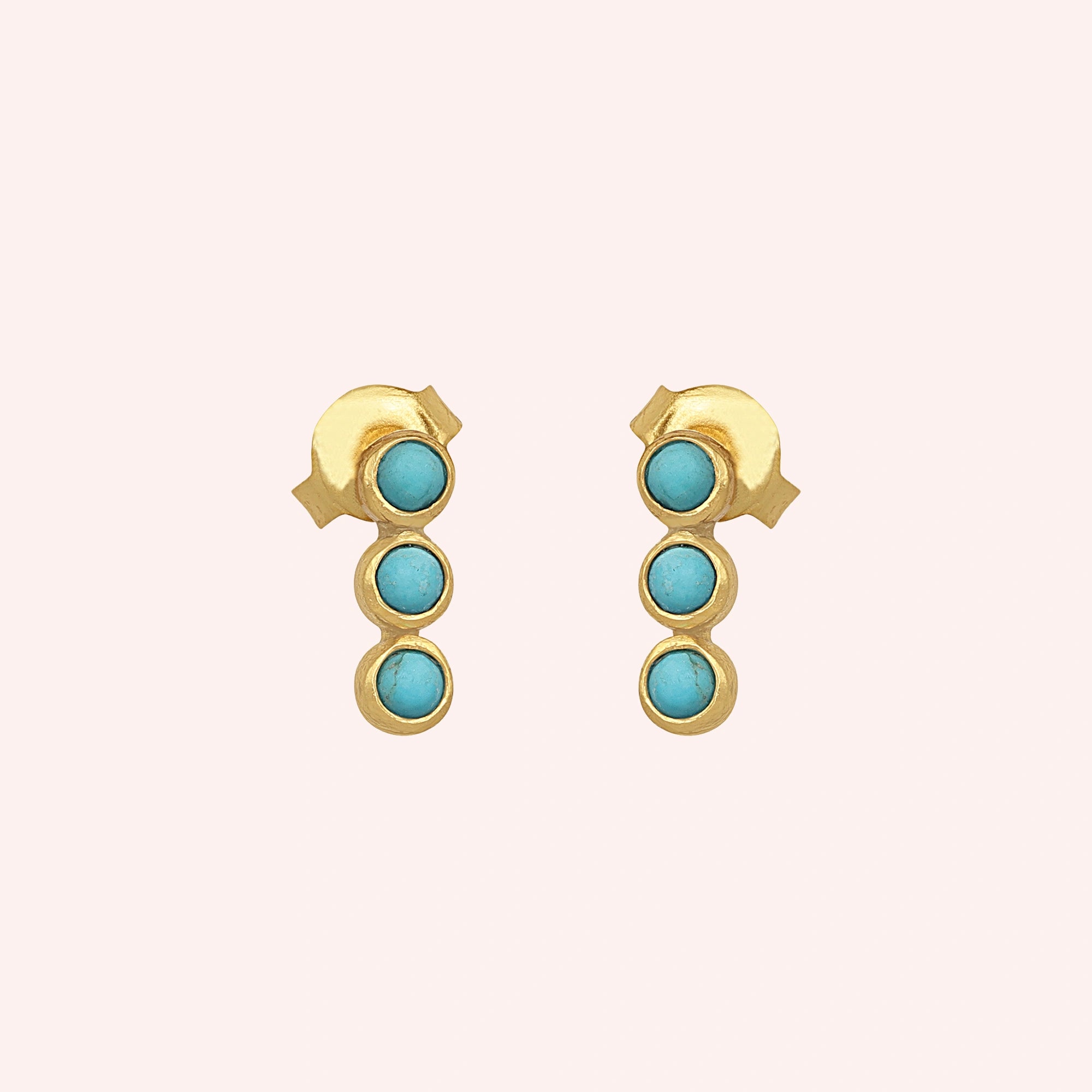 Turquoise earrings featuring three stones on gold-plated silver stud earrings over a pink background front angle