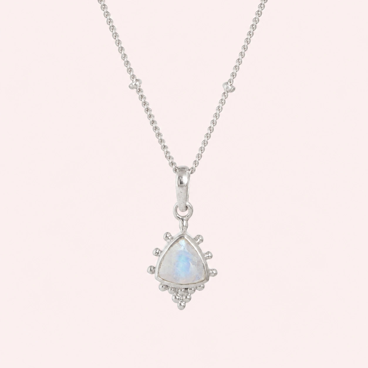 Simple_necklace_with_triangular_moonstone_pendant_sterling_silver_at_front_angle_on_solid_pink_background