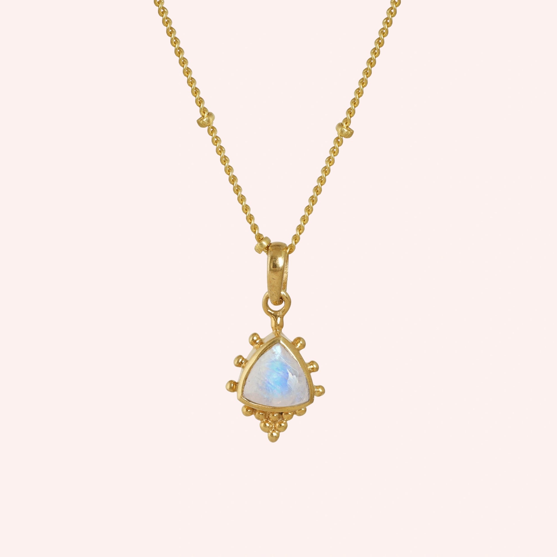 Simple_necklace_with_triangular_moonstone_pendant_gold_plated_silver_at_front_angle_on_solid_pink_background