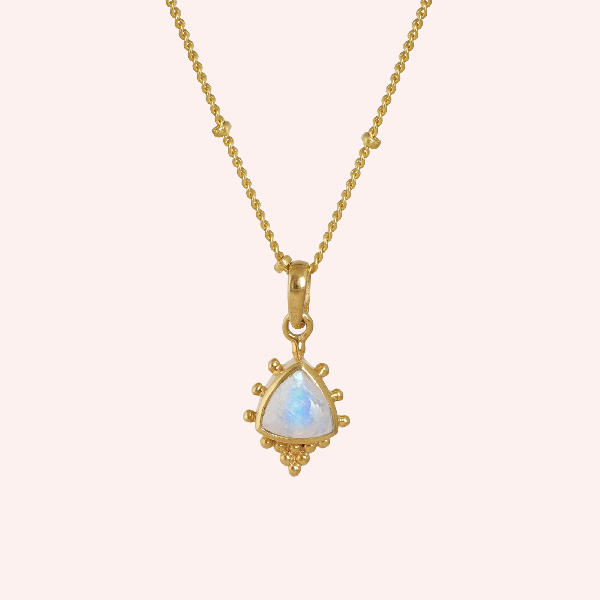 Simple_necklace_with_triangular_moonstone_pendant_gold_plated_silver_at_front_angle_on_solid_pink_background