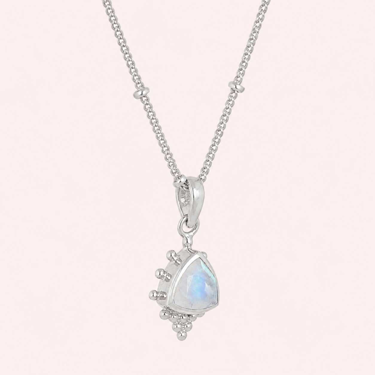 Simple_necklace_with_triangular_moonstone_pendant_sterling_silver_at_slightly_angled_on_solid_pink_background