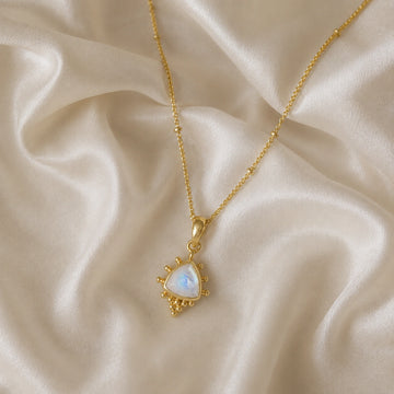 Simple_necklace_with_triangular_moonstone_pendant_gold_plated_silver_at_slightly_angled_on_soft_fabric_background