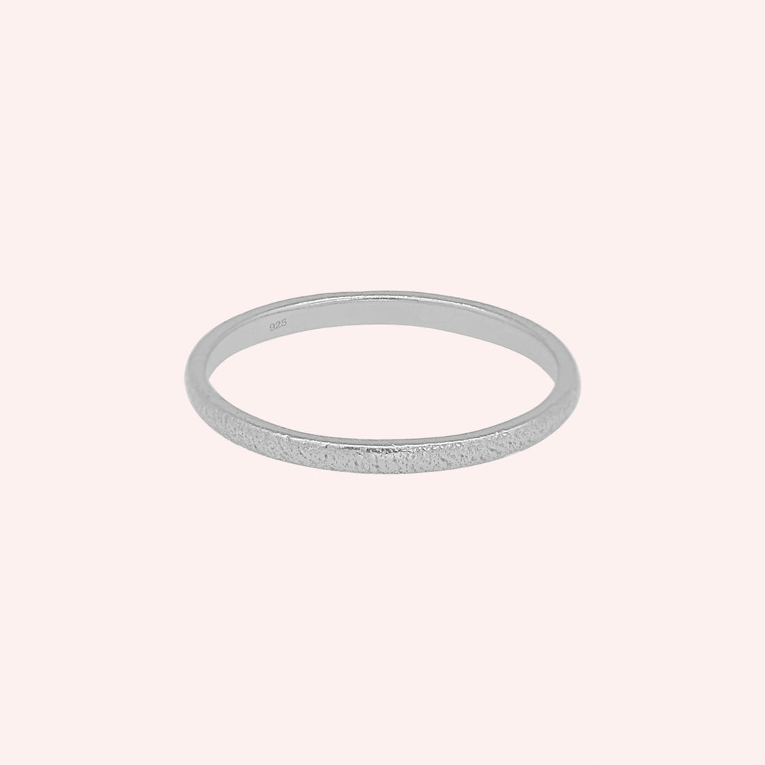 Simple_ring_in_gold_plated_silver_with_a_textured_band_at_front_angle_on_solid_pink_background