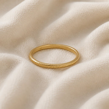 Simple_ring_in_gold_plated_silver_with_a_textured_band_at_front_angle_on_soft_fabric_background