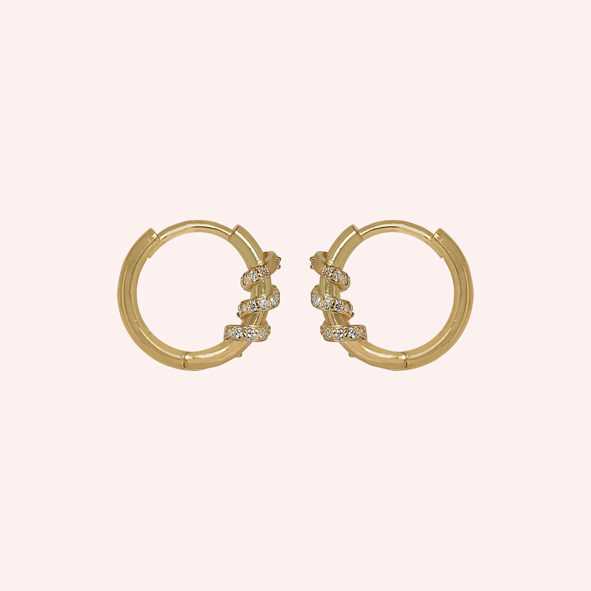 Small_hoop_earrings_in_gold_plated_silver_with_a_twisted_design_band_at_side_angle_view_on_solid_pink_background