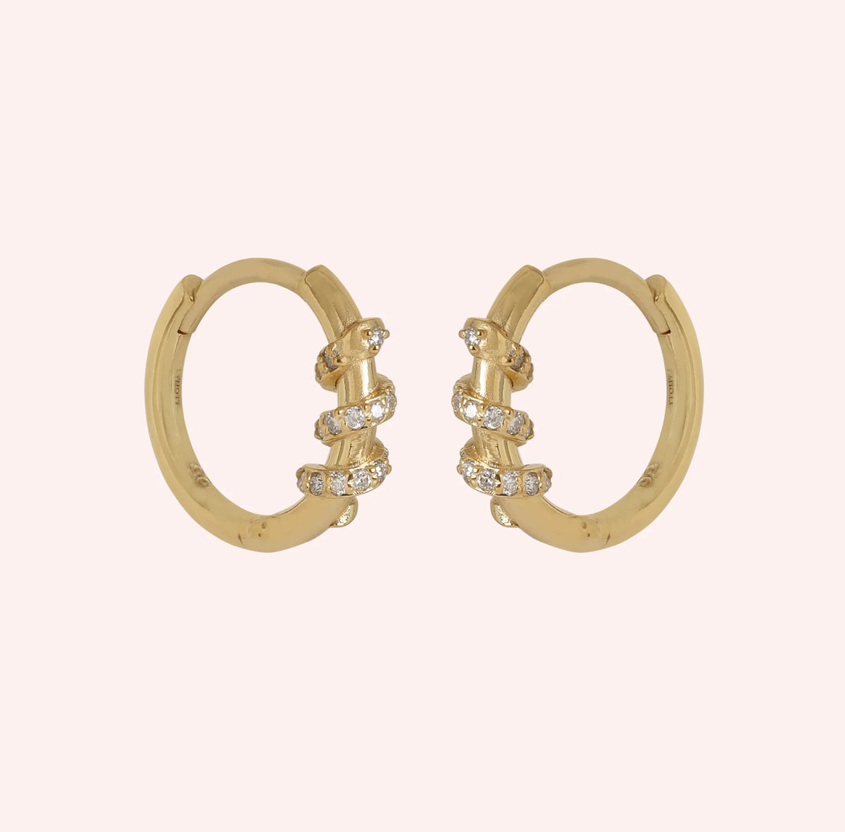 Small_hoop_earrings_in_gold_plated_silver_with_a_twisted_design_band_at_side_angle_view_on_solid_pink_background