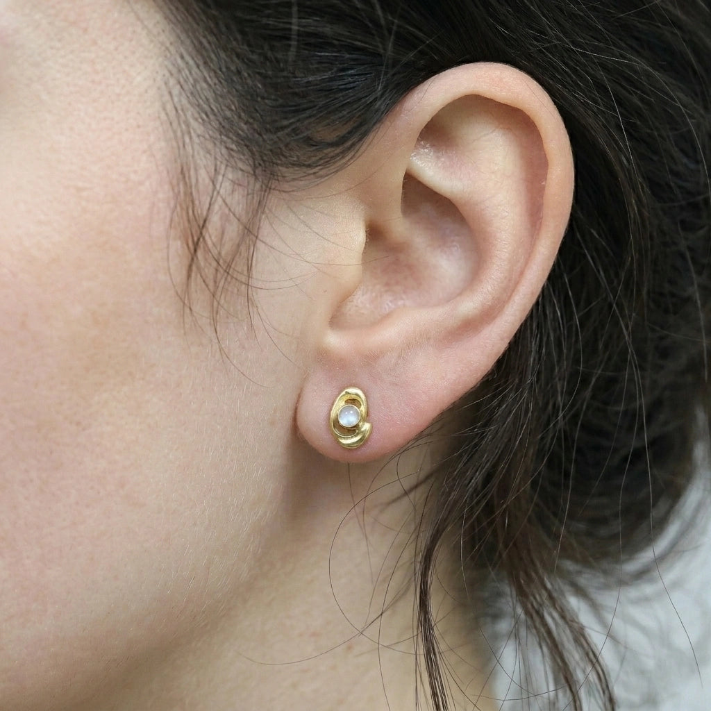 Small-stud-earrings-with-moonstone-gold-plated-silver-wordn-by-a-model-in-a-natural-light