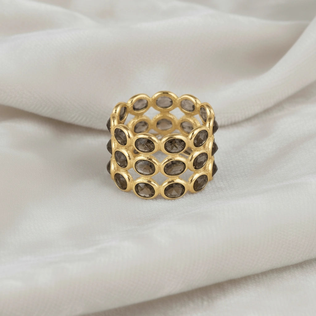 Horizontal close up shot of a wide gold-plated sterling silver smoky quartz ring on a white velvet background with oval stones