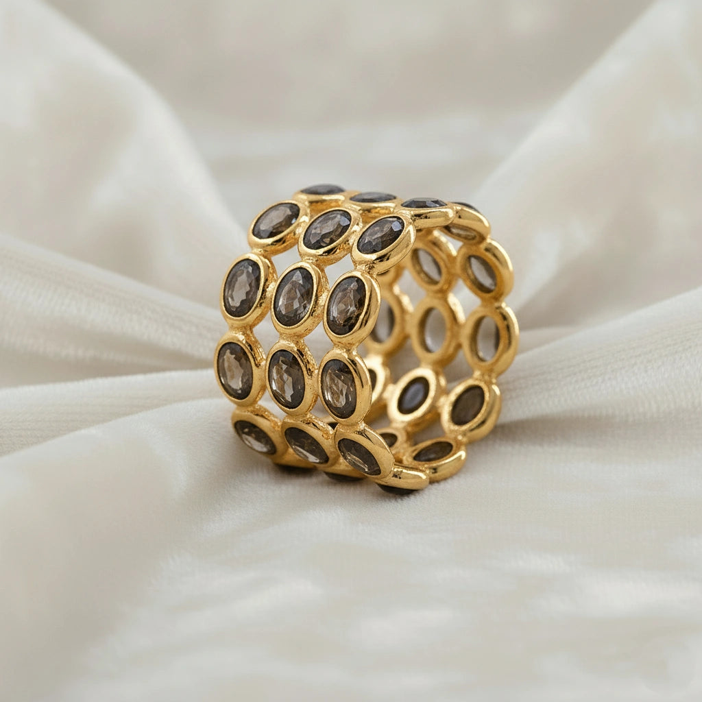 Angled close up shot of a wide gold-plated sterling silver smoky quartz ring on a white background with oval smoky quartz stones