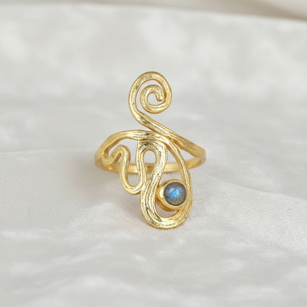 gold plated solar ring crystal ring shown at a front angle view featuring a labradorite stone on white fabric background