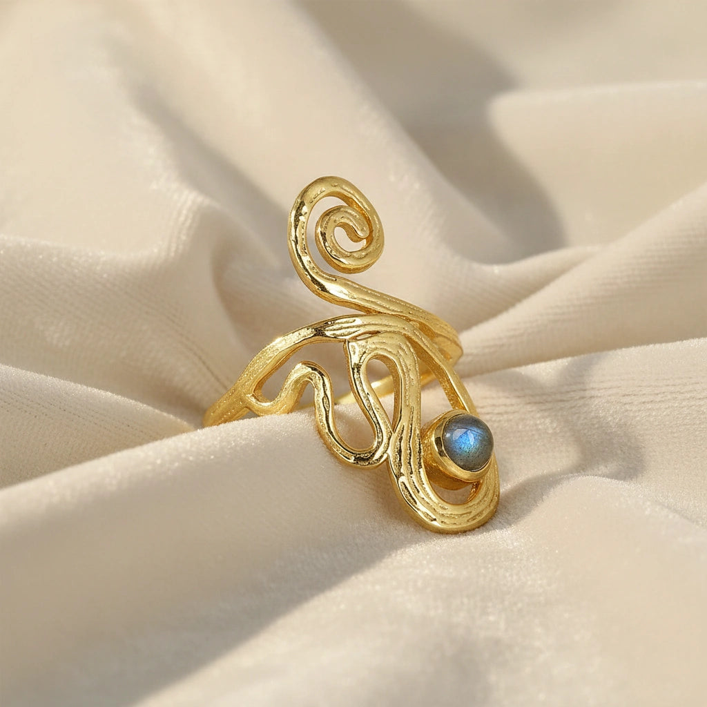 gold plated solar ring crystal ring shown at a side angle view featuring a labradorite stone on white fabric background