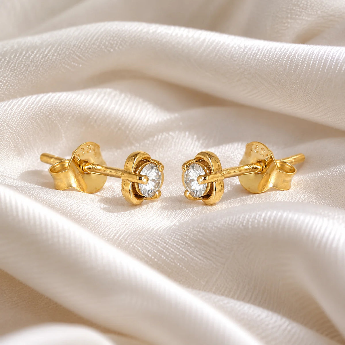 Solitaire_earrings_in_gold_plated_silver_in_a_floral_design_at_slight_angle_view_on_soft_fabric_background