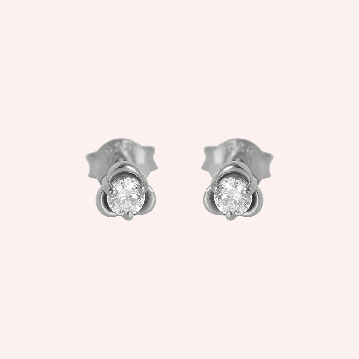 Solitaire_earrings_in_sterling_silver_with_a_round_lab_grown_diamond_at_front_angle_view_on_solid_pink_background