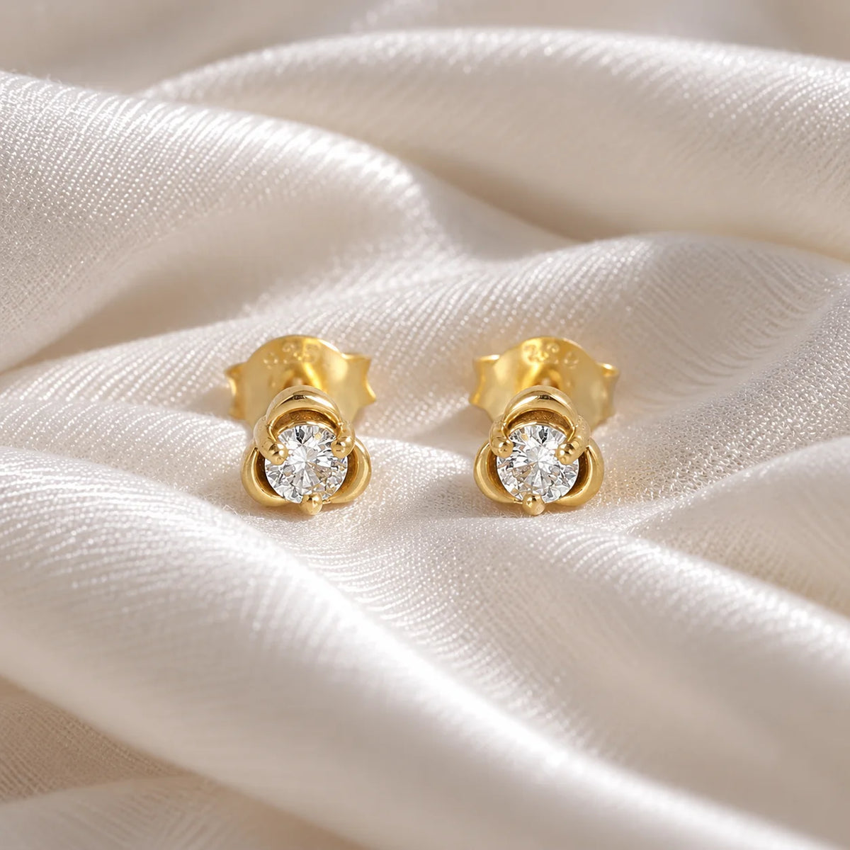 Solitaire_earrings_in_gold_plated_silver_in_a_floral_design_at_front_angle_view_on_soft_fabric_background