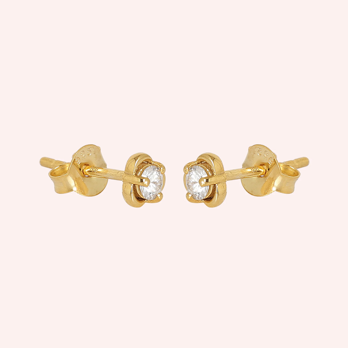 Solitaire_earrings_in_gold_plated_silver_with_a_round_lab_grown_diamond_at_side_angle_view_on_solid_pink_background