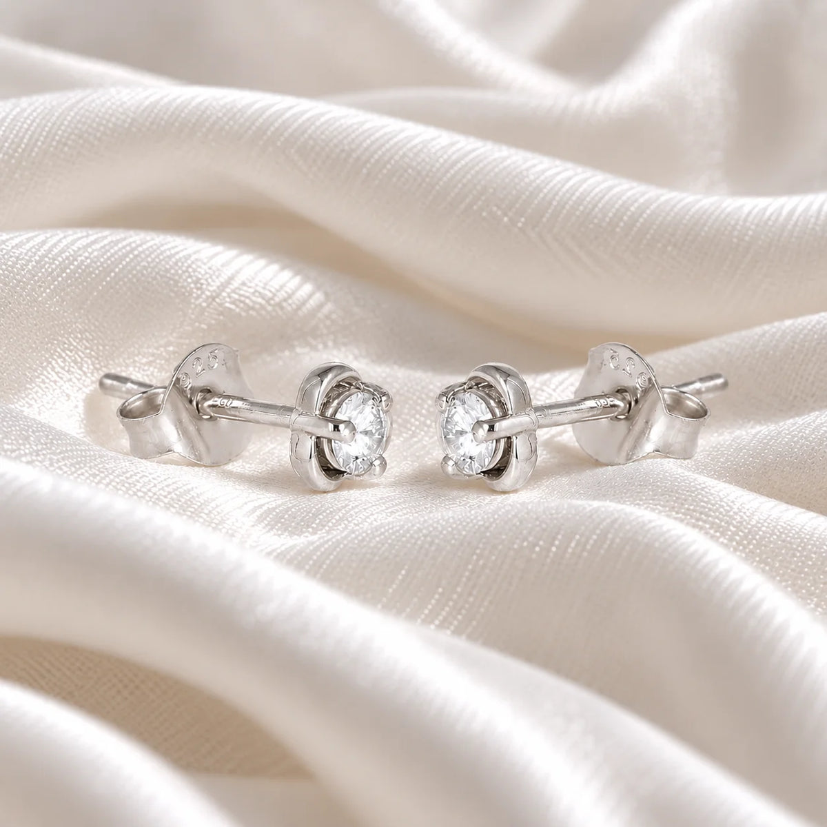 Solitaire_earrings_in_sterling_silver_in_a_floral_design_at_slight_angle_view_on_soft_fabric_background