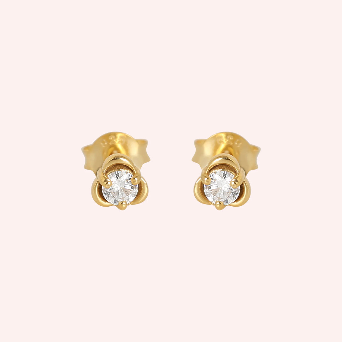 Solitaire_earrings_in_gold_plated_silver_with_a_round_lab_grown_diamond_at_front_angle_view_on_solid_pink_background