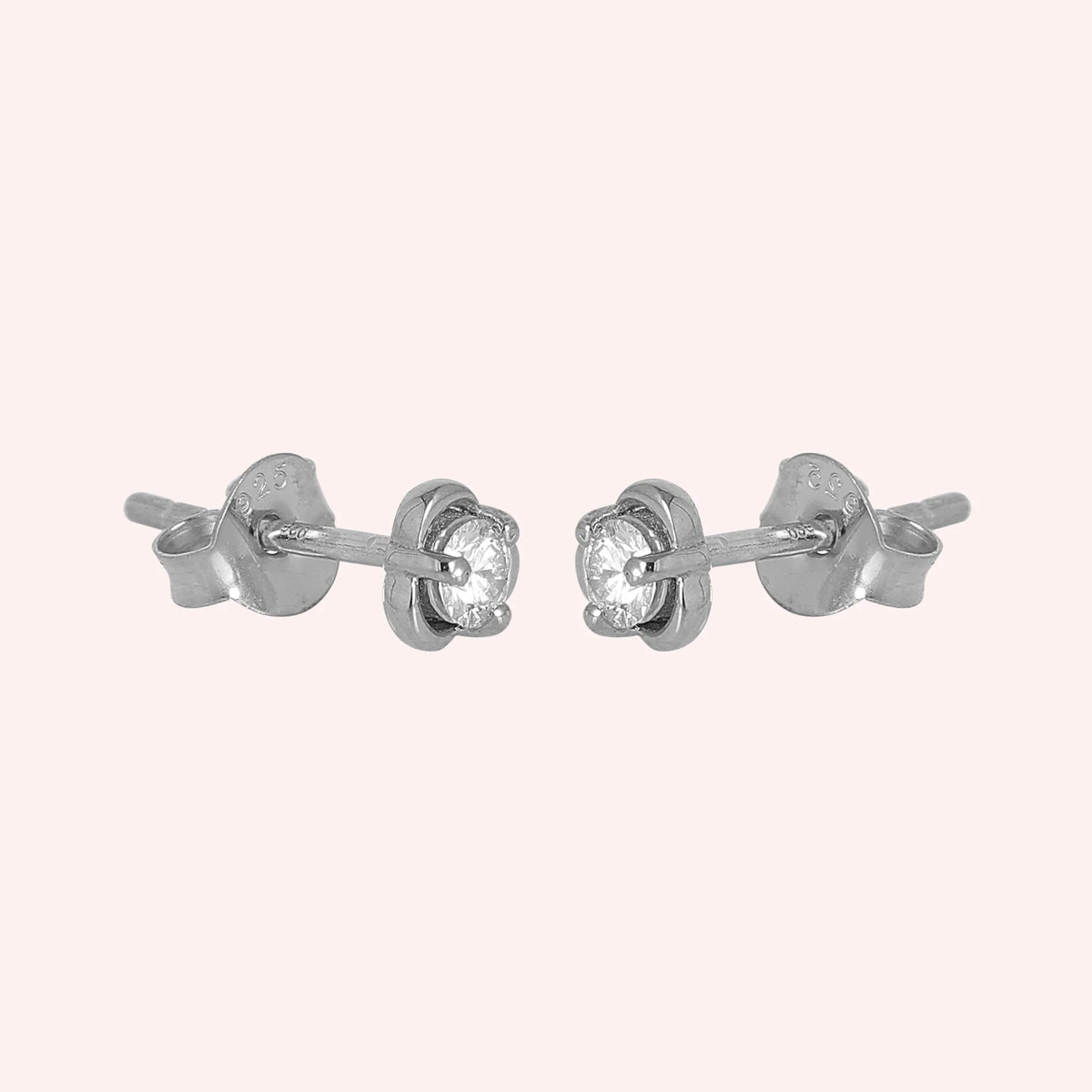 Solitaire_earrings_in_sterling_silver_in_a_floral_design_at_slight_angle_view_on_solid_pink_background