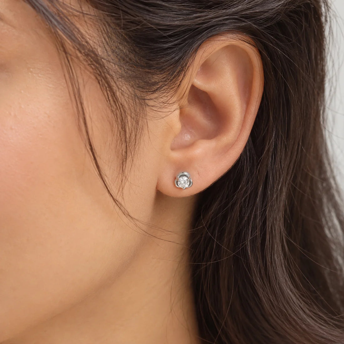 Solitaire_earrings_in_gold_plated_silver_with_a_round_lab_grown_diamond_at_side_angle_view_on_soft_fabric_background