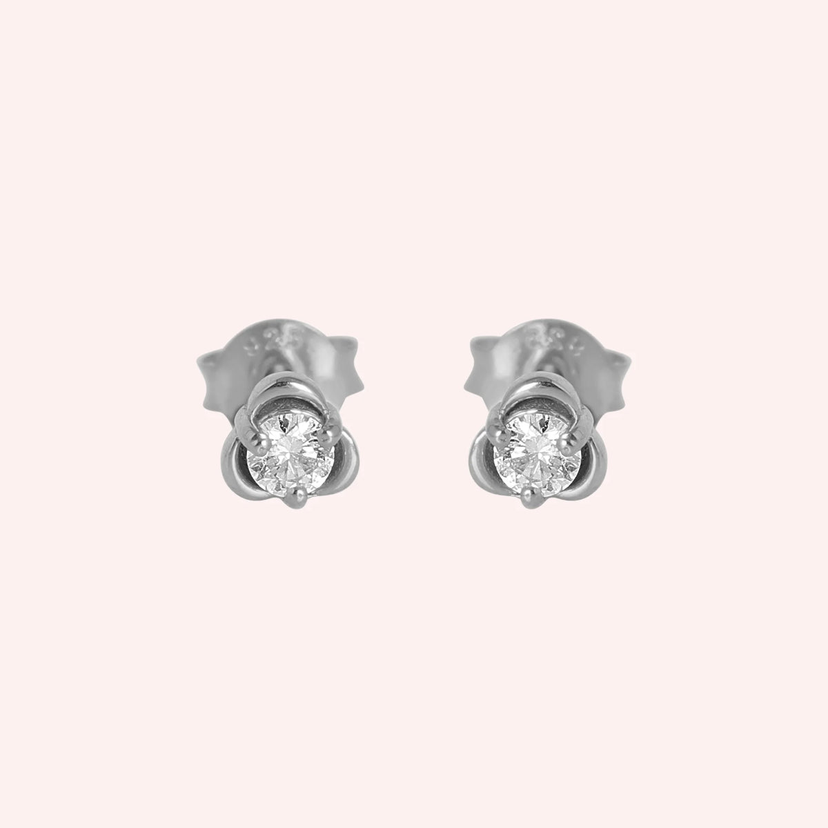 Solitaire_earrings_in_sterling_silver_in_a_floral_design_at_front_angle_view_on_solid_pink_background