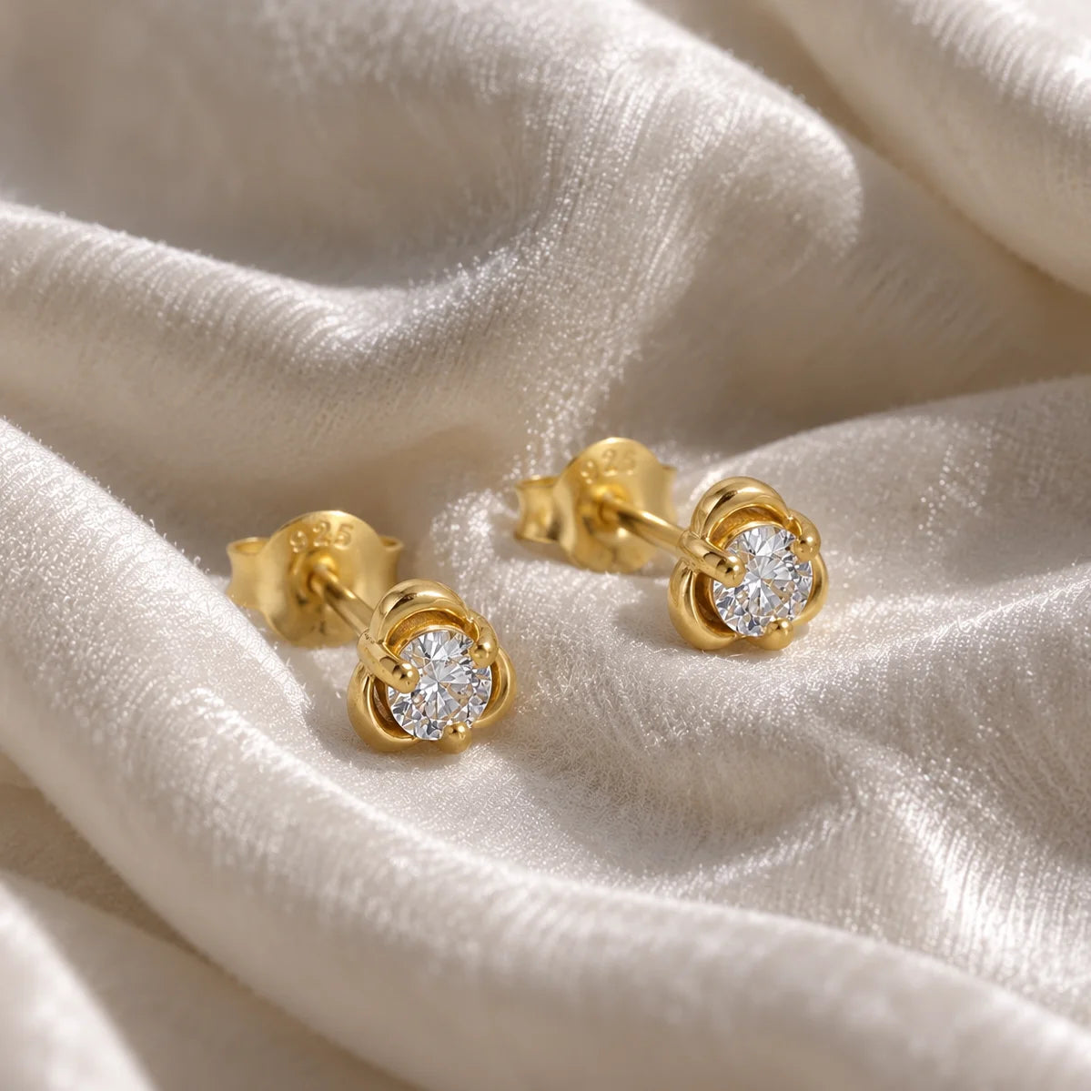 Solitaire_earrings_in_gold_plated_silver_with_a_round_lab_grown_diamond_at_side_angle_view_on_soft_fabric_background