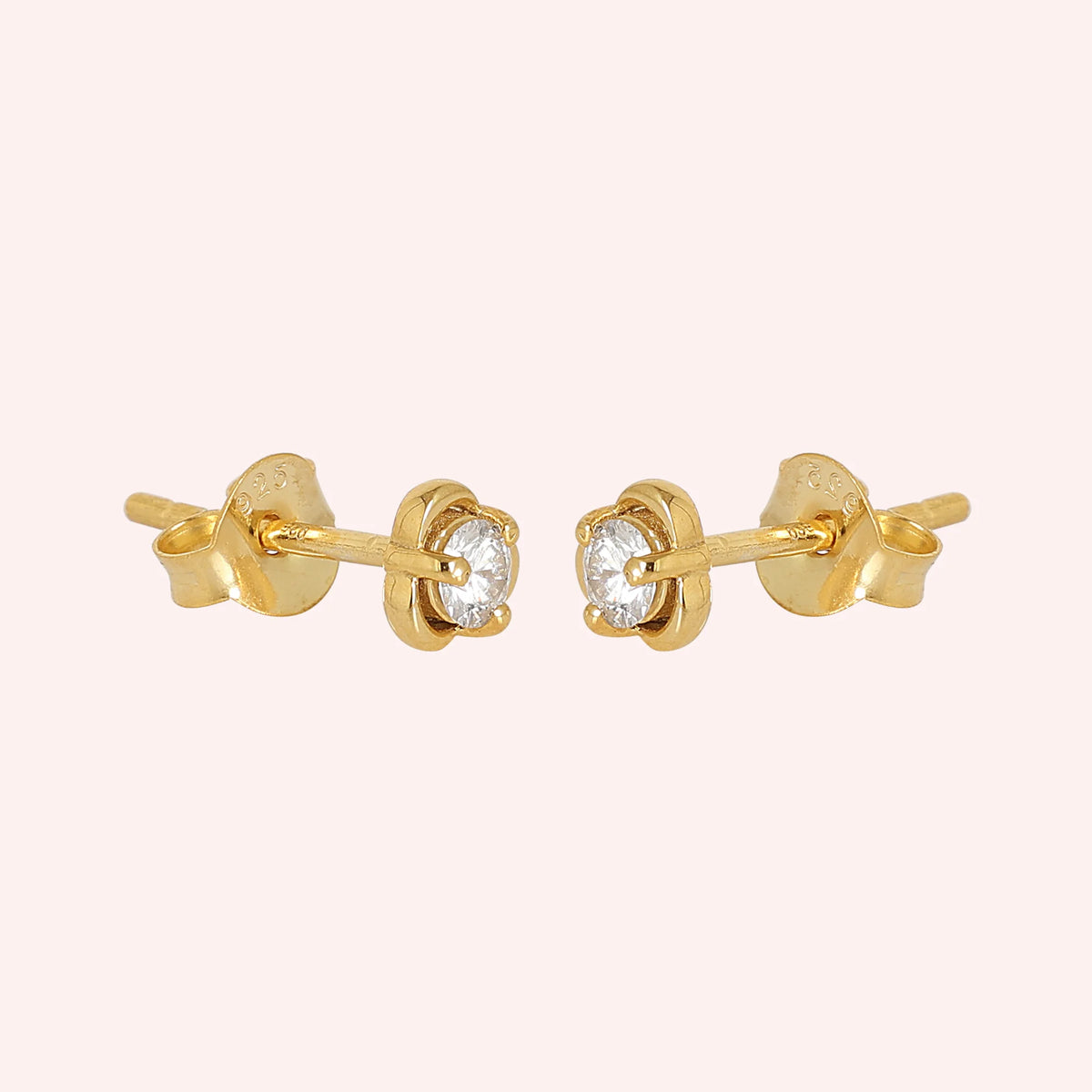 Solitaire_earrings_in_gold_plated_silver_in_a_floral_design_at_slight_angle_view_on_solid_pink_background