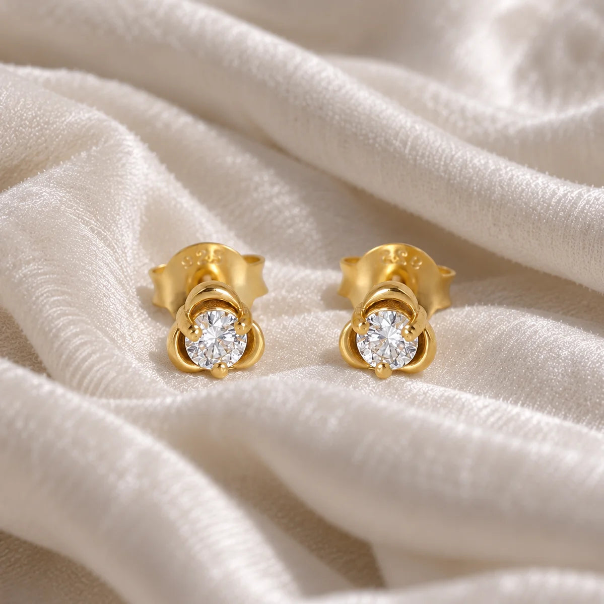 Solitaire_earrings_in_gold_plated_silver_with_a_round_lab_grown_diamond_at_front_angle_view_on_soft_fabric_background