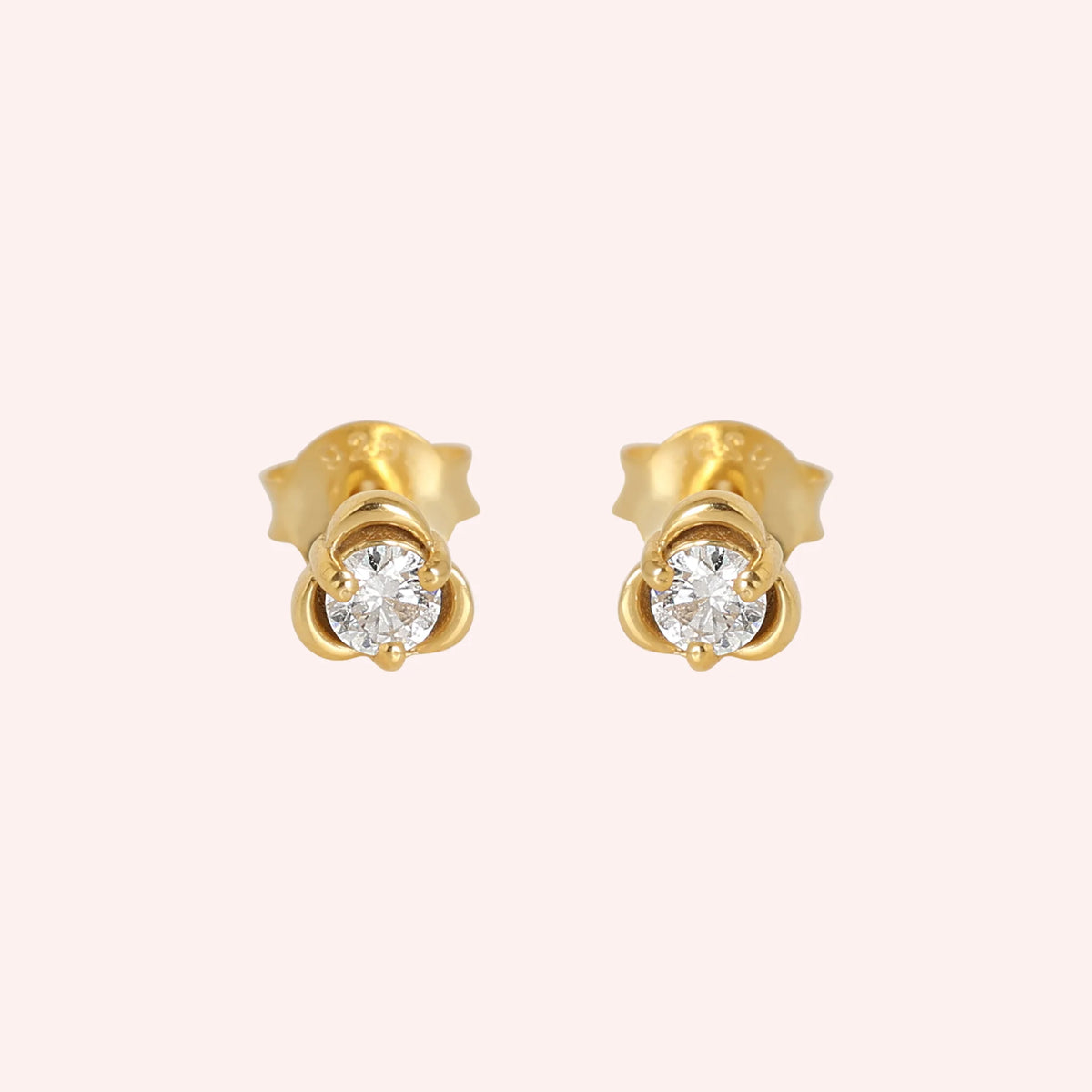 Solitaire_earrings_in_gold_plated_silver_in_a_floral_design_at_front_angle_view_on_solid_pink_background
