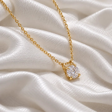 Solitaire_necklace_in_gold_plated_silver_with_a_round_lab_grown_diamond_at_side_angle_view_on_soft_fabric_background