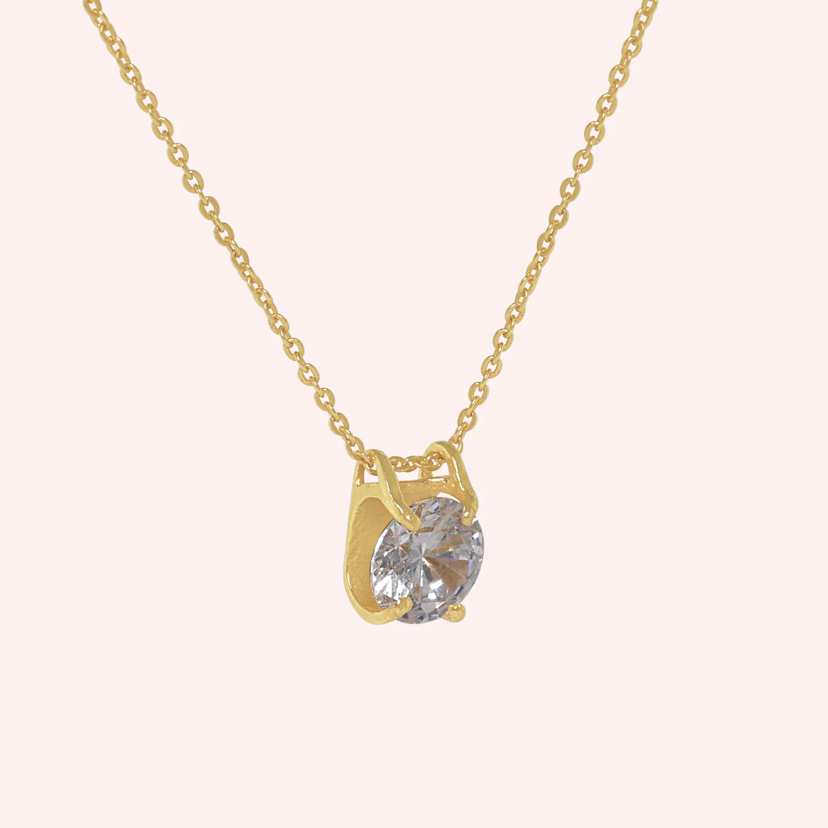 Solitaire_necklace_in_gold_plated_silver_with_a_round_lab_grown_diamond_at_side_angle_view_on_solid_pink_background