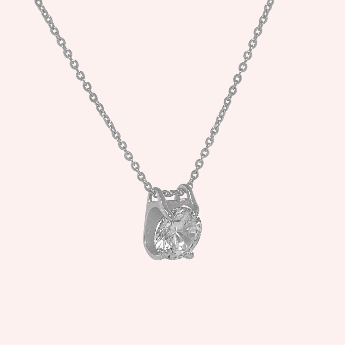 Solitaire_necklace_in_sterling_silver_with_a_round_lab_grown_diamond_at_side_angle_view_on_solid_pink_background