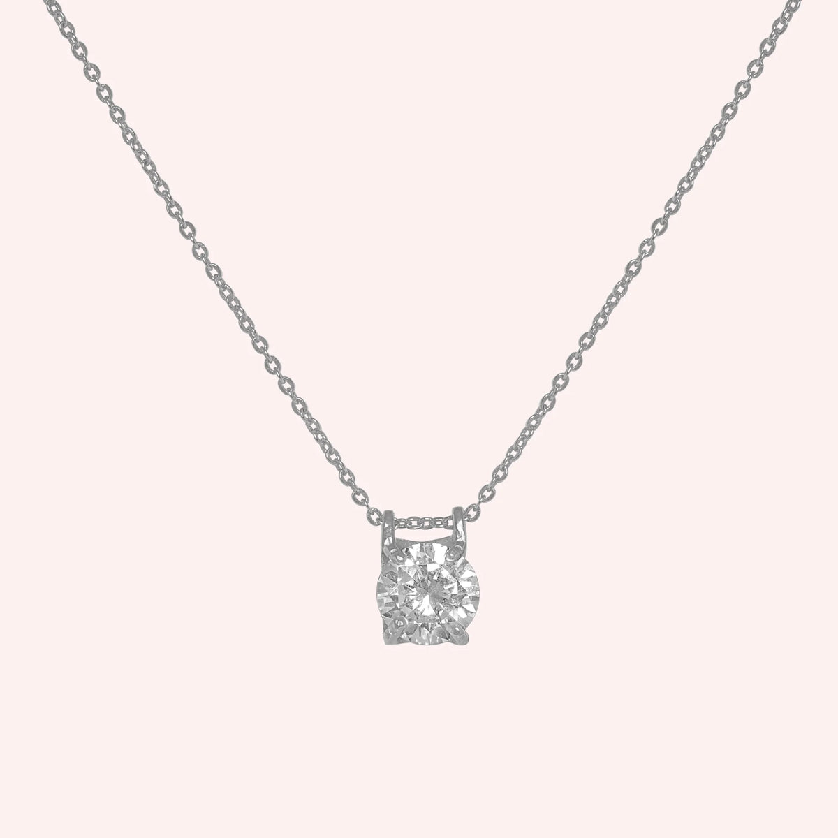 Solitaire_necklace_in_sterling_silver_with_a_round_lab_grown_diamond_at_front_angle_view_on_solid_pink_background