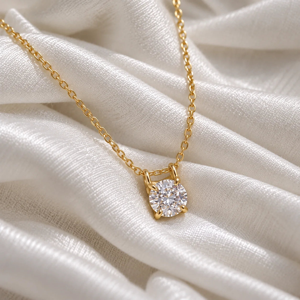 Solitaire_necklace_in_gold_plated_silver_with_a_round_lab_grown_diamond_at_front_angle_view_on_soft_fabric_background
