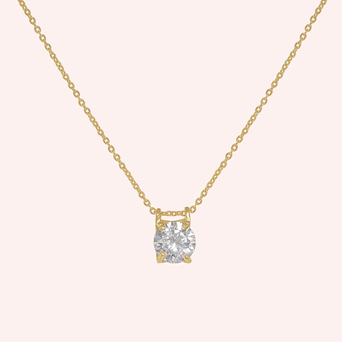 Solitaire_necklace_in_gold_plated_silver_with_a_round_lab_grown_diamond_at_front_angle_view_on_solid_pink_background