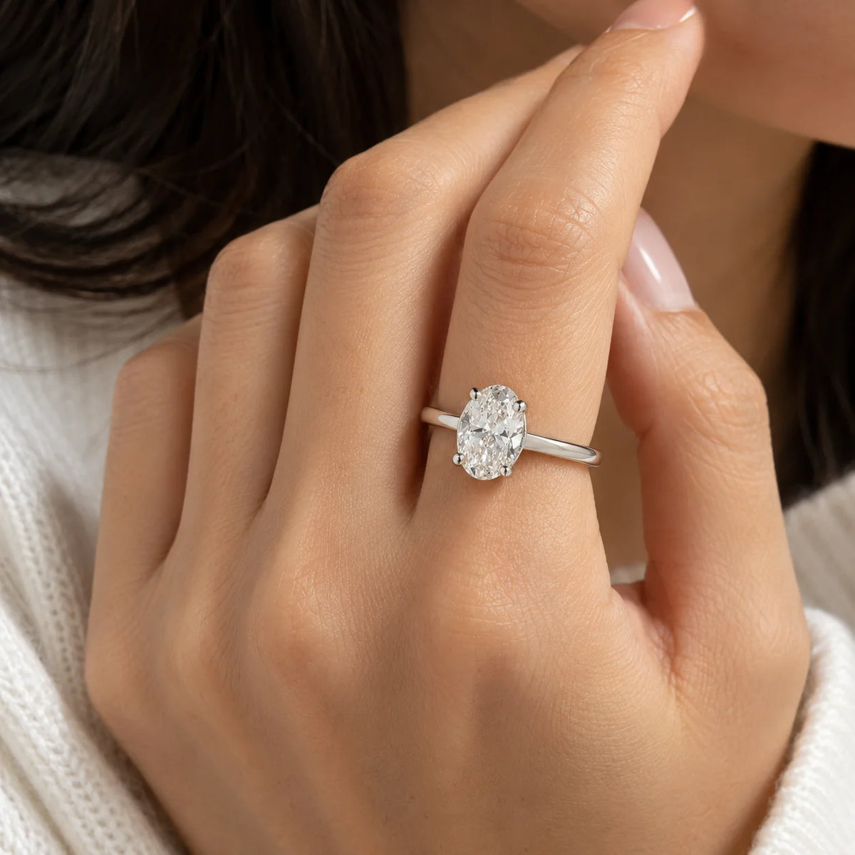 Solitaire_ring_in_gold_plated_silver_with_an_oval_CZ_stone_at_front_angle_view_worn_by_a_model