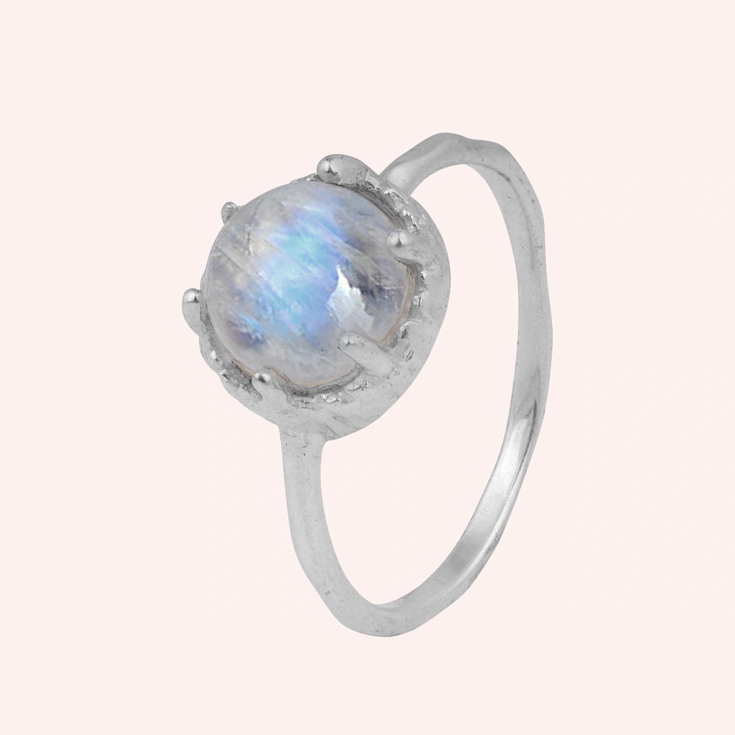 Solitaire_ring_in_sterling_ring_with_round_moonstone_shown_in_slightly_angled_view_on_solid_pink_background