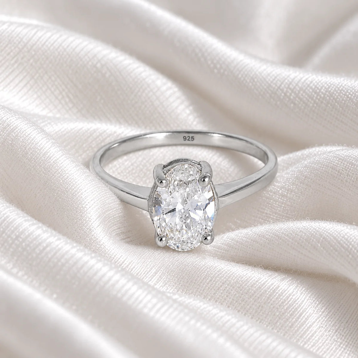 Solitaire_ring_in_sterling_silver_with_an_oval_CZ_stone_at_front_angle_view_on_soft_fabric_background