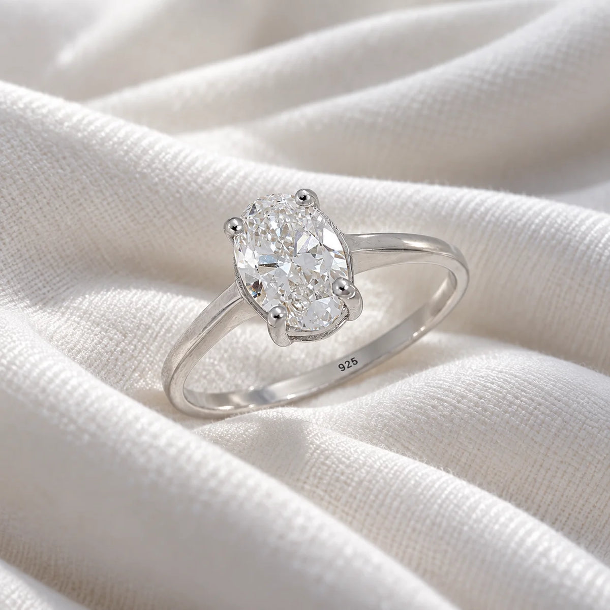 Solitaire_ring_in_sterling_silver_with_an_oval_lab_grown_diamond_at_slightly_angle_view_on_soft_fabric_background