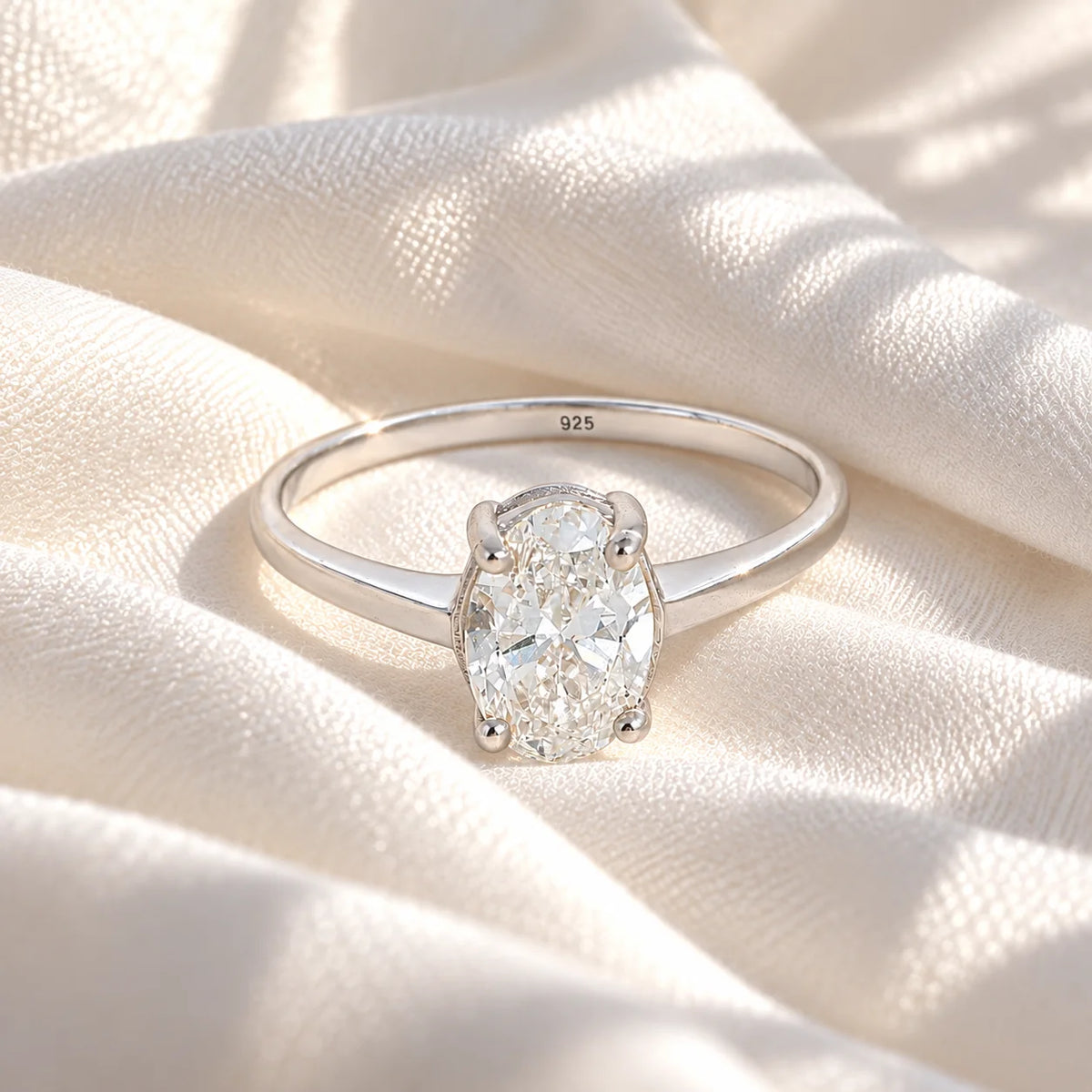 Solitaire_ring_in_sterling_silver_with_an_oval_lab_grown_diamond_at_front_angle_view_on_soft_fabric_background