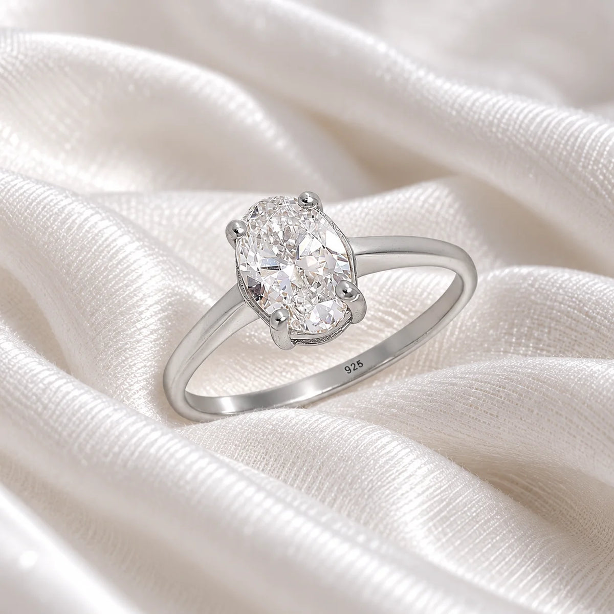 Solitaire_ring_in_sterling_silver_with_an_oval_CZ_stone_at_side_angle_view_on_soft_fabric_background