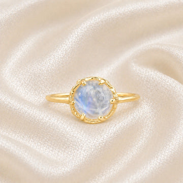 Solitaire_ring_in_gold_plated_ring_with_round_moonstone_shown_in_front_angle_view_on_soft_fabric_background