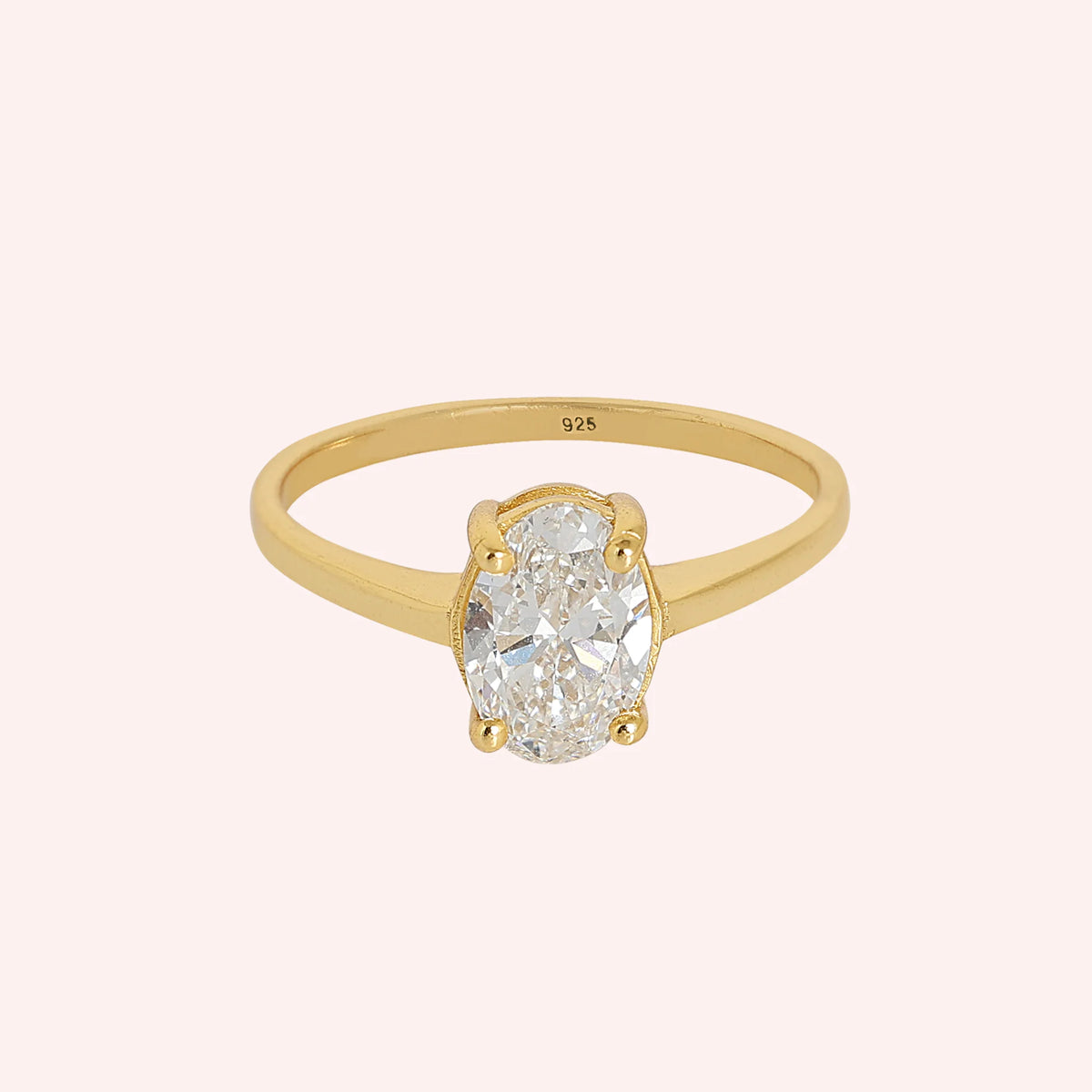 Solitaire_ring_in_gold_plated_silver_with_an_oval_lab_grown_diamond_at_front_angle_view_on_solid_pink_background