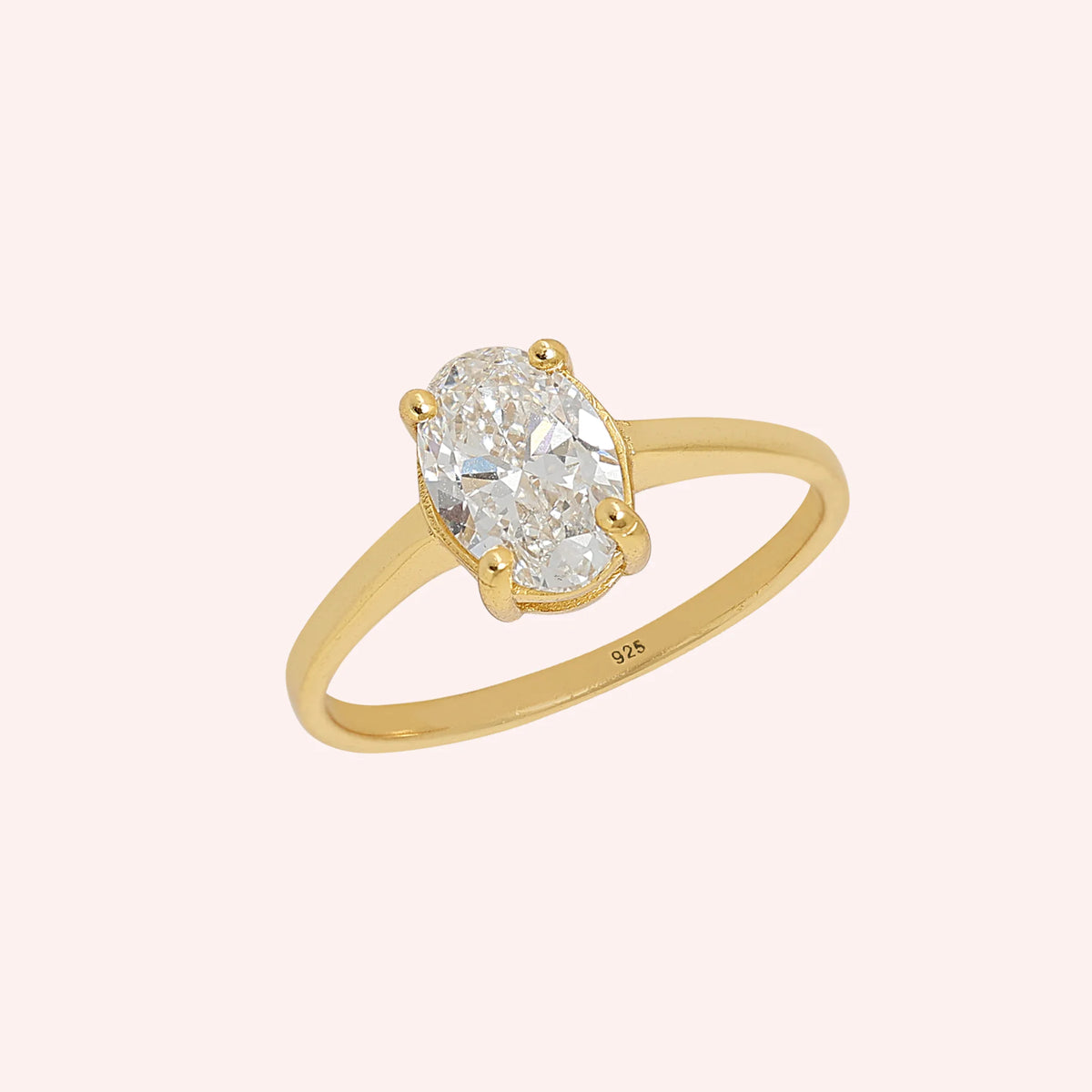 Solitaire_ring_in_gold_plated_silver_with_an_oval_lab_grown_diamond_at_slightly_angle_view_on_solid_pink_background