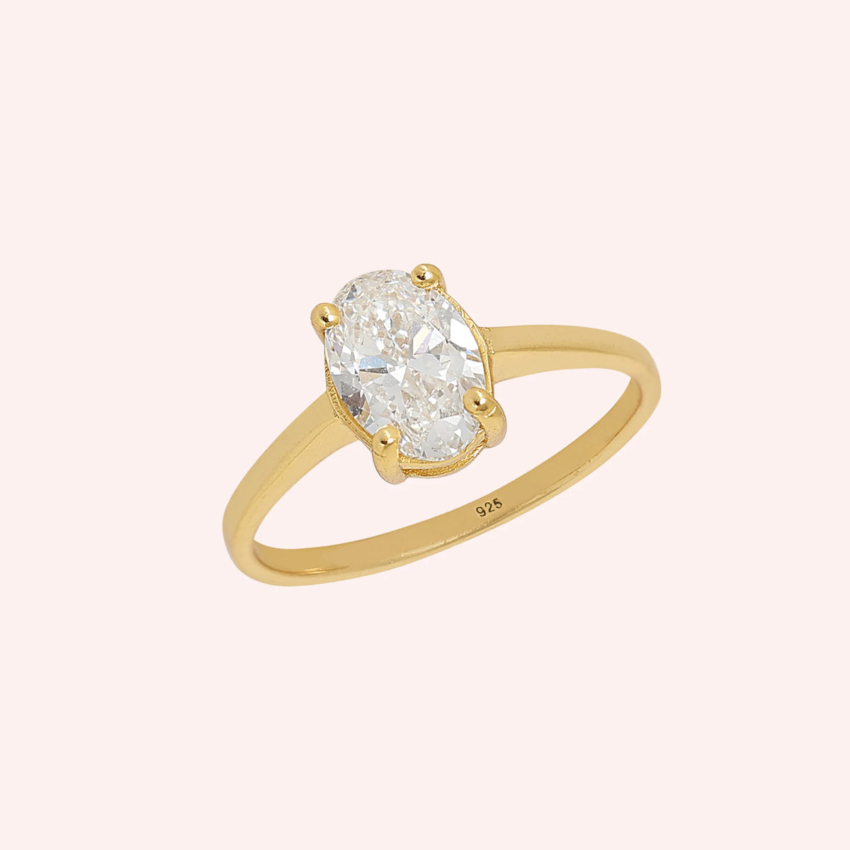 Solitaire_ring_in_gold_plated_silver_with_an_oval_CZ_stone_at_side_angle_view_on_solid_pink_background